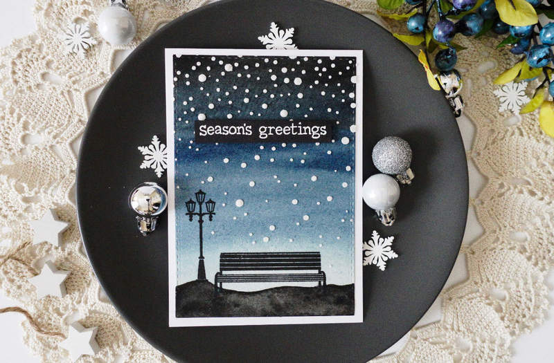 Handmade Christmas card with watercoloured night sky and falling snow using the Texture Paste from ranger and silhouettes of a bench and a lamp for a snowy night in the park look using the “Winter In The Park” stamp set by Lawn Fawn.