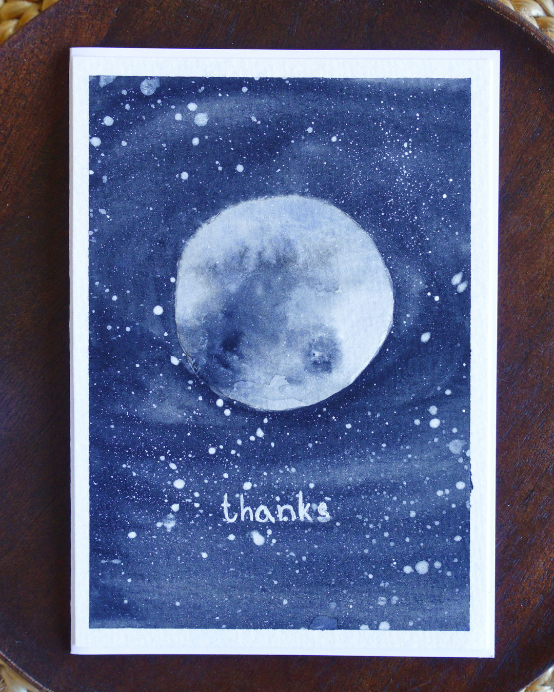 Simple card with watorcoloured moon with dark sky and starry sky background.